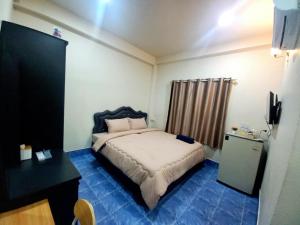 a small bedroom with a bed and a desk at Wari My Home in Betong