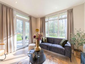 - un salon avec un canapé et de grandes fenêtres dans l'établissement Vakantie woning "Huisje Boszicht", à Haarle