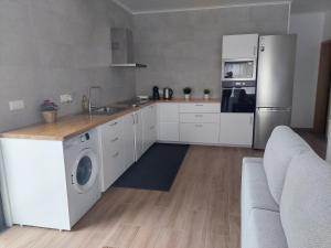 a kitchen with white cabinets and a washer and dryer at Casa Loja do Xavier in Ponta Delgada