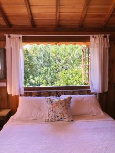 a bedroom with a bed with a large window at Pousada Vilarejo das Oliveiras in Queimada