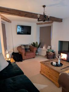 a living room with a couch and a tv at Cosy country cottage with log fireplace and views in Kendal