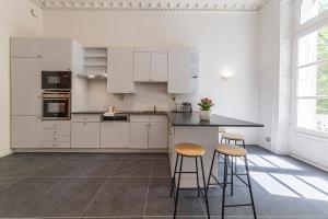 Una cocina con gabinetes blancos y taburetes de bar. en Le Roi René - XIXe siècle - Château, en Angers