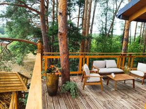 a wooden deck with a couch and chairs on it at ForRest House Domki na drzewie niedaleko Suntago in Budy Mszczonowskie +11 photos