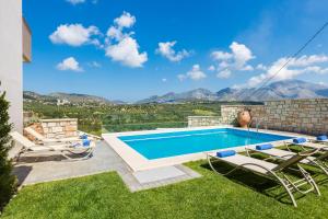 a swimming pool with chairs and a view of mountains at Renta Villas, vivid experience, By ThinkVilla in Perama