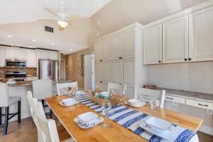 a kitchen and dining room with a wooden table and white cabinets at Casa Palmera by SkyRun Anna Maria in Bradenton +50 photos