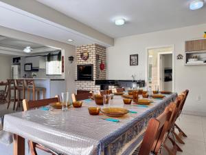 a dining room with a long table and a kitchen at Casa 404 - Aconchegante a 350m do mar em Bombas - Ideal para famílias! in Bombinhas