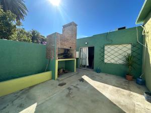 a house with a green wall and a brick fireplace at Casa independiente con estufa a leña in Minas