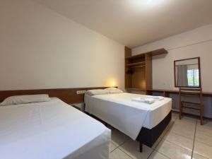 a hotel room with two beds and a chair at Hotel Graju Itajaí in Itajaí