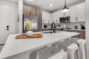 a kitchen with a counter with a sink and two stools at Vibrant 1 Bedroom Paradise Pool and Gym Bliss in Apollo Beach +37 photos
