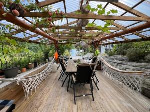 a wooden deck with a table and chairs under a roof at #Beautiful outdoor area and cozy small cottage# in Fotlandsvåg