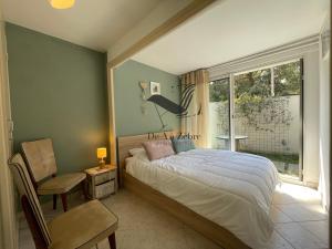 a bedroom with a bed and a chair and a window at La Petite Cèpe - Au bord de la plage et de la forêt in La Tremblade