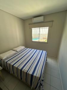 a bedroom with a bed with a blue and white striped blanket at Casa Porto Mar in Aracaju