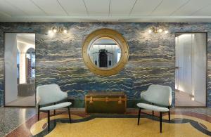 a wall with a mirror and two chairs at Grand Hotel Savoia in Genoa