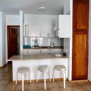 a kitchen with a white counter and two stools at Apt In Colina 2, Los Cristianos K105 in El Guincho