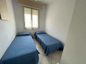 two beds in a small room with two windows at Residence Lido adriano baia tartaruga private beach included in Lido Adriano +2 photos
