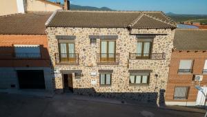un vieux bâtiment en pierre avec des fenêtres et un balcon dans l'établissement Casa Rural La Cerecera, à Los Navalucillos