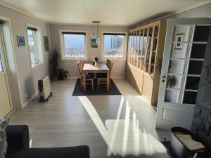 a dining room with a table and chairs and windows at Skjærgårdsidyll in Askøy