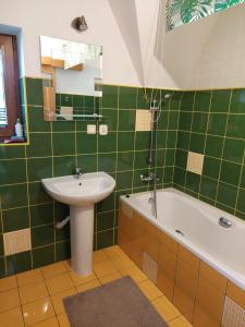 a green tiled bathroom with a sink and a tub at Pokoje u Micka Poronin 5 km od Zakopanego in Poronin