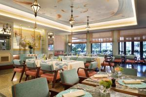a dining room with tables and chairs and windows at Grand Hotel Savoia in Genoa