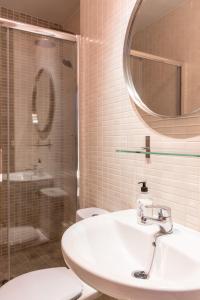 een badkamer met een wastafel, een douche en een spiegel bij Arenal Maestranza Apartment in Sevilla +53 foto's