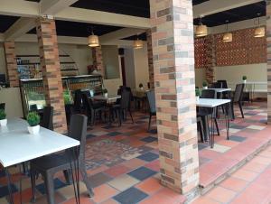 a restaurant with tables and chairs and a brick pillar at Hostal La Cabaña Tayrona in Santa Marta