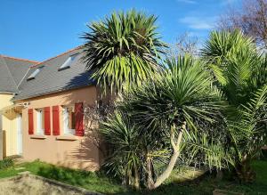 a house with two palm trees in front of it at Brennig in Penmarch