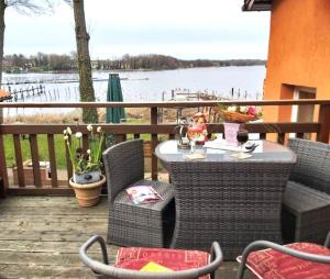 a table and chairs on a deck with a view of the water at FeWo Alpenstube in Neue Scheune