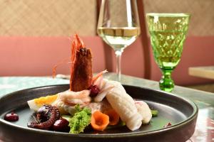 a plate of food on a table with a glass of wine at Grand Hotel Savoia in Genoa