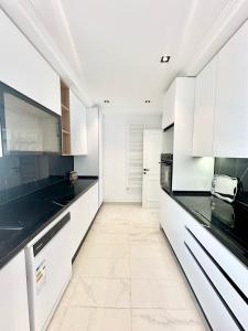 une cuisine avec des armoires blanches et des comptoirs noirs dans l'établissement Jasmine Appartement, à La Marsa 5 autres photos