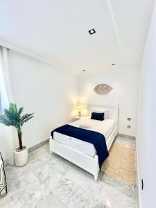 une chambre blanche avec un lit et une plante en pot dans l'établissement Jasmine Appartement, à La Marsa