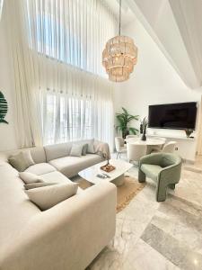 un salon blanc avec un canapé et une télévision dans l'établissement Jasmine Appartement, à La Marsa