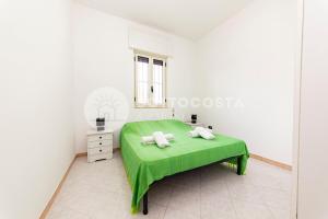 ein weißes Zimmer mit einem grünen Bett und einem Fenster in der Unterkunft Coral Reef in Torre Specchia Ruggeri