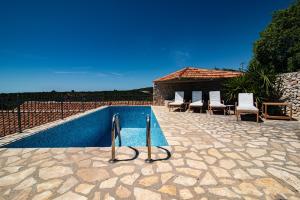 a swimming pool with chairs next to a house at Paradise cottage in Vinišće