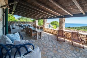 a patio with chairs and a table and a stone wall at Paradise cottage in Vinišće