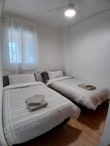 two beds in a white room with towels on them at Appartement cosy avec 2 chambres et piscine commune in San Pedro del Pinatar