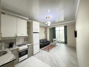 a kitchen with white cabinets and a living room at Etno Naz in Bishkek