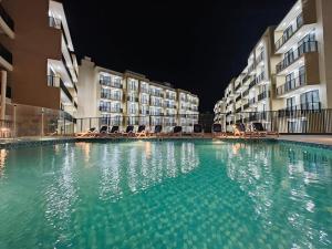 a swimming pool in front of some buildings at night at Private Beach 1BR-Yacht Club-Work Space-Pool-Gym in Ras al Khaimah +42 photos