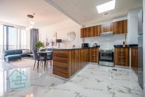 a kitchen with wooden cabinets and a living room at Private Beach 1BR-Yacht Club-Work Space-Pool-Gym in Ras al Khaimah