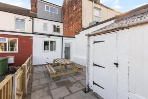 un patio con 2 porte bianche e un tavolo da picnic di Pickin Cottage a Altofts Altre 6 foto