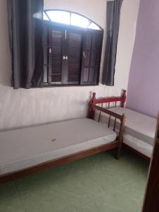 two beds in a room with a window at Sua paz está aqui in Mongaguá