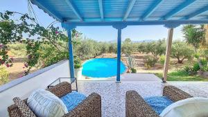a patio with chairs and a swimming pool at Hydra Bay Seaside Villa with Pool in Thermisia