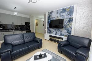 a living room with two black leather couches and a tv at Sara apartment in Vlorë