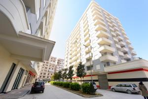 a tall white building with cars parked in front of it at Sara apartment in Vlorë