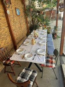 a long table with plates on it with two chairs at PGL in bucataria mamei- cazare la tara in Mălîncrav +4 photos