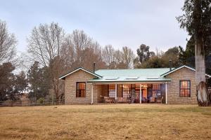 a brick house with a green roof on a field at Bergview Farm Cottage by First Private Stays in Underberg