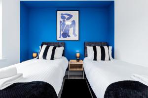 zwei Betten in einem Zimmer mit blauen Wänden in der Unterkunft Contractors Wow! 5 Bedrooms 10 Guests Free Parking in Basingstoke