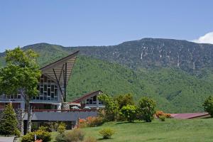 a building with a mountain in the background at Okushiga Kogen Hotel in Yamanouchi