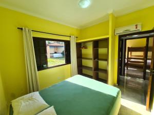 a yellow bedroom with a bed and a window at Chalés individuais com piscina a 500M da praia in Massaguassu +19 photos