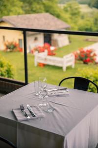 a white table with wine glasses and a view of a garden at Tenuta Bellingeri - Locanda del Barco in Sant' Agata fossili