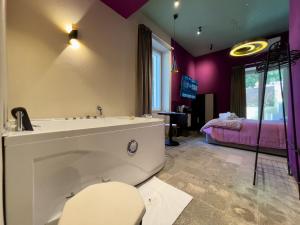a bathroom with a tub and a bed with purple walls at Residencia Barrio B&b - 3 suites - 6 Minutes from Amalfi Coast in Cava deʼ Tirreni